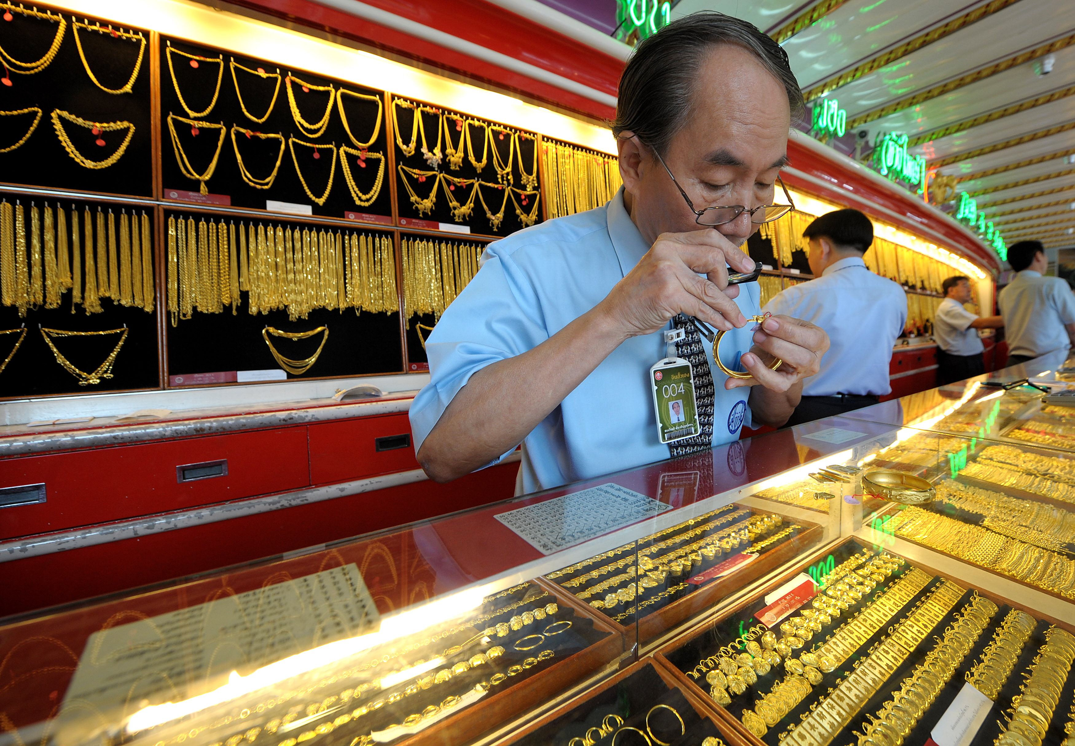A Thai gold seller inspects a gold brace